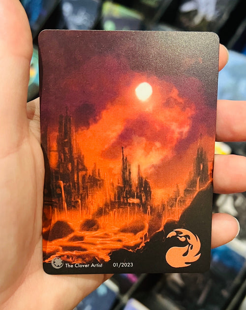 Hand holding a collectible card with a fiery landscape design against a blurred background of similar cards.