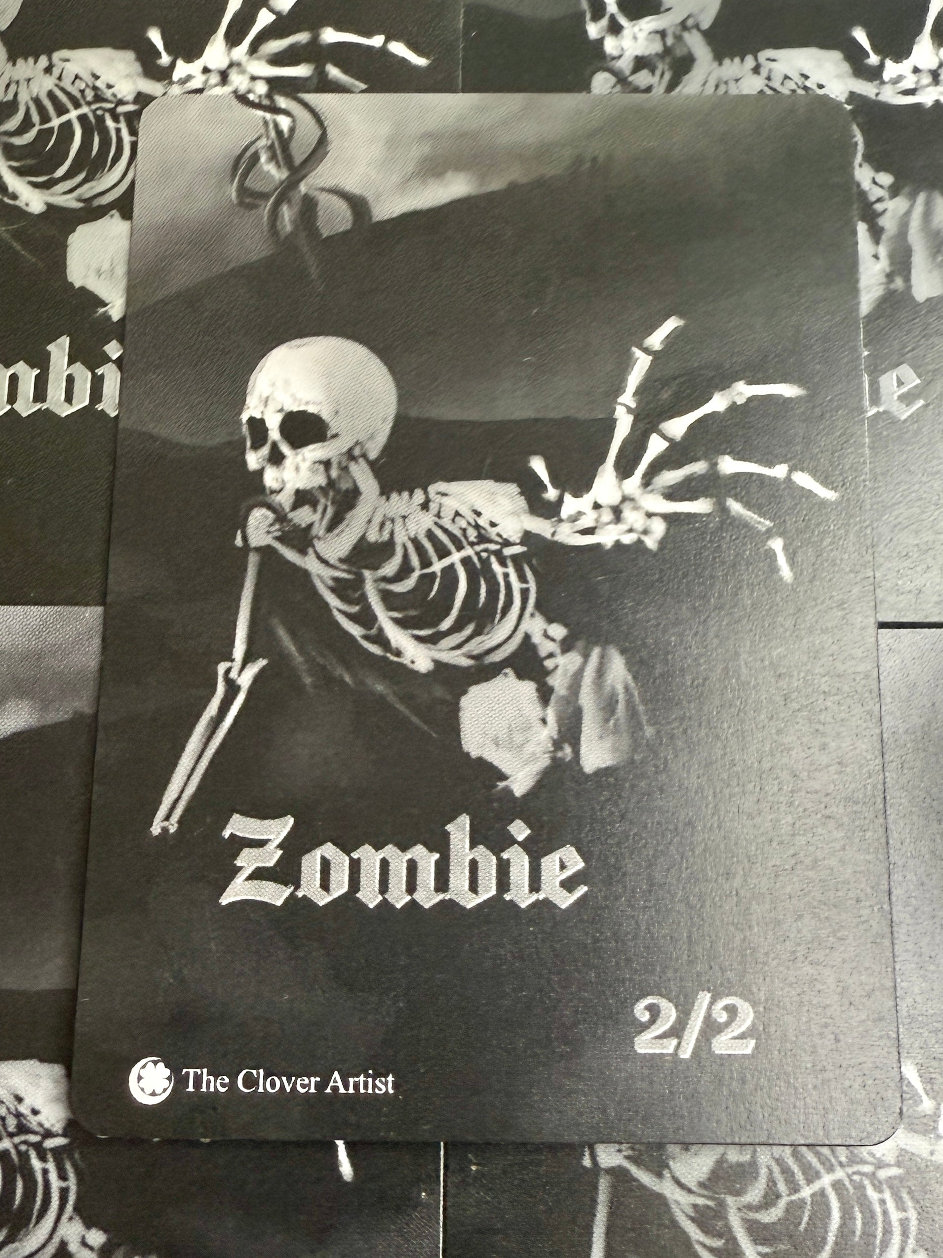 Black and white card with a skeleton and 'Zombie' text, featuring 'The Clover Artist' branding.