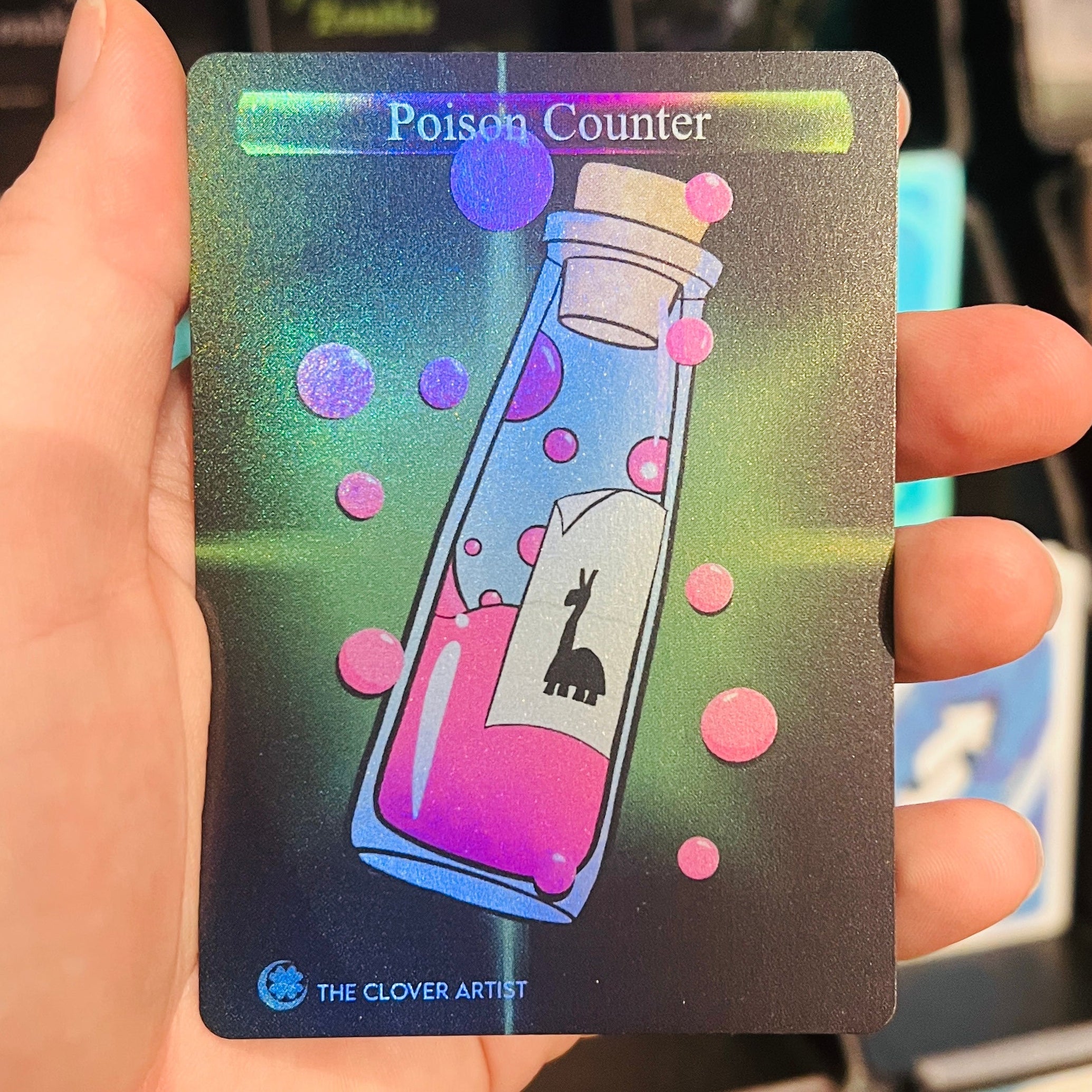 Card with a bottle illustration labeled 'Poison Counter' held by a hand against a blurred card game backdrop.